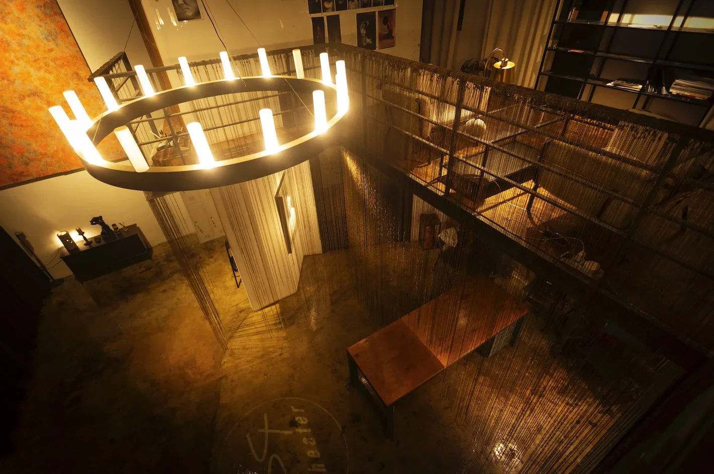 An overhead view of P4 Theater showing a circular light fixture, hanging string curtains, tables, and an upper walkway.
